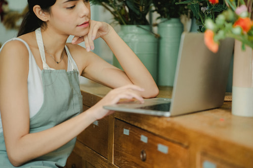 Focused woman working on laptop in shop.